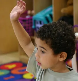 Photo of a child raising their hand.