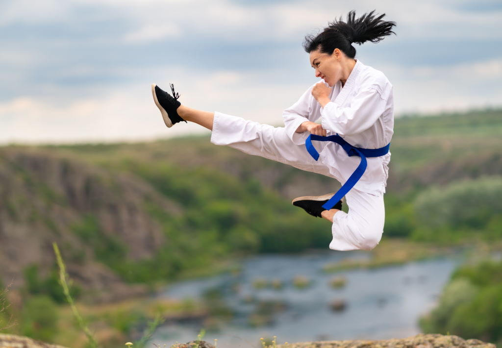 A woman performing a flying martial arts kick that showcases agility, decisiveness, and velocity.